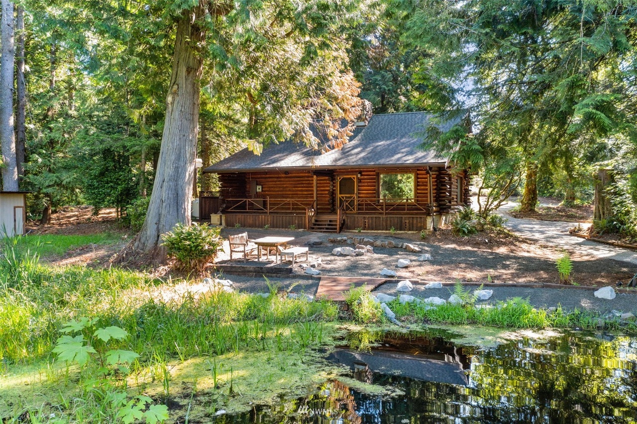 Custom log cabin STR exterior set on 25 acres of old-growth forest with a pond