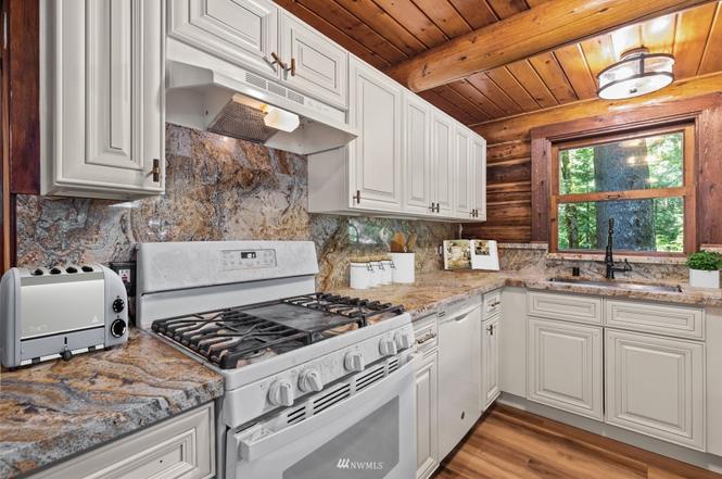 Updated cabin kitchen with granite counters and white cabinetry