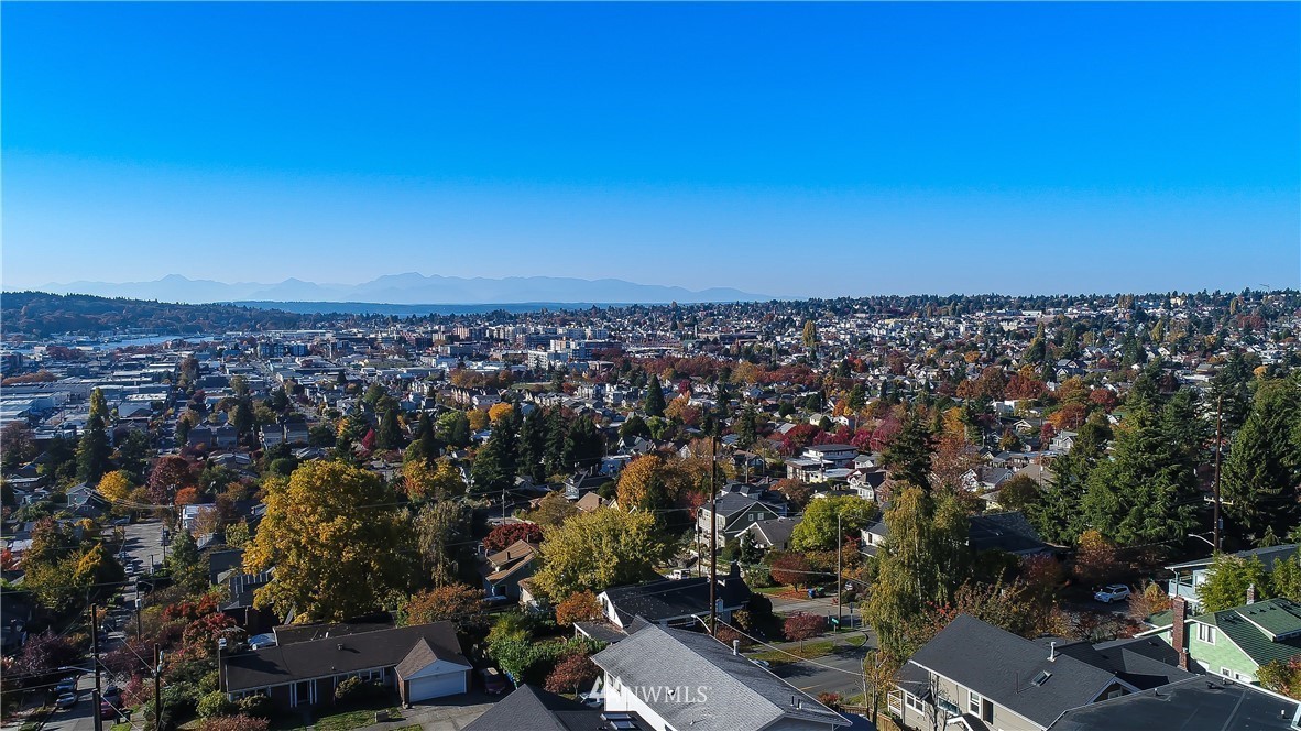Aerial neighborhood view with fall foliage, city skyline, and distant mountains