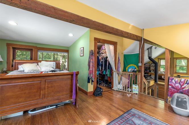 Casita bedroom with wood floors, exposed beam, and adjacent loft space